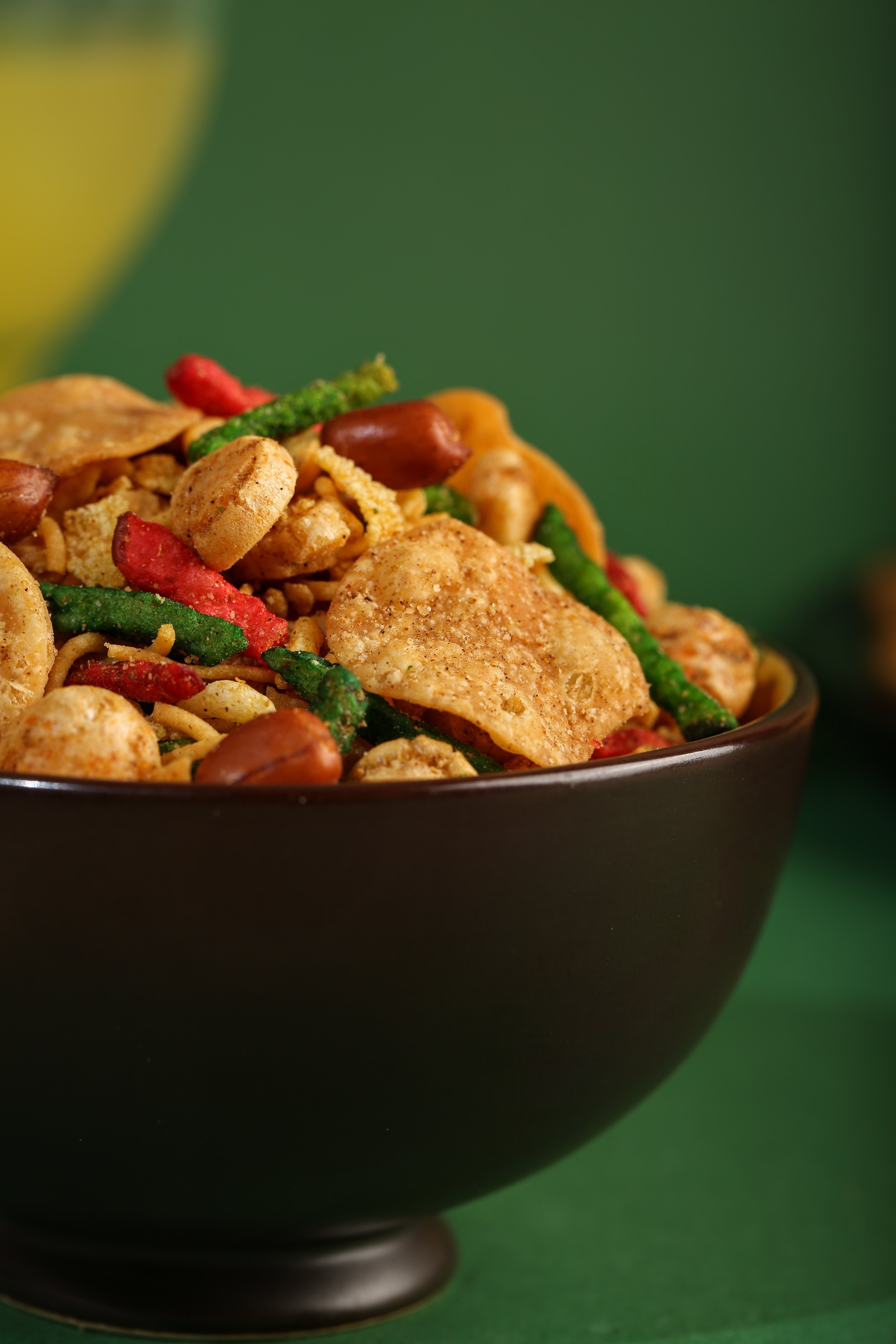 Colorful crunchy snack mix with chips, peanuts, and spices spilling from a bowl